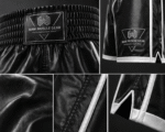 Close up of high-quality black satin fabric and reinforced white piping on custom boxing trunks.