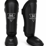 Black premium shin and instep guards with high-density foam, PU leather, and secure hook-and-loop straps by Wani Muscle Gear for boxing, MMA, kickboxing, and Muay Thai.