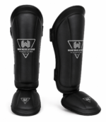 Black premium shin and instep guards with high-density foam, PU leather, and secure hook-and-loop straps by Wani Muscle Gear for boxing, MMA, kickboxing, and Muay Thai.
