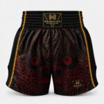 Custom boxing shorts with gold Wani logo and red tribal sublimation print, product close-up