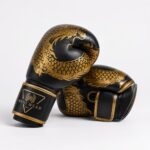 Custom Wani Wear boxing gloves dragon design close-up — synthetic leather texture, gold trim stitching, wrist logo detail